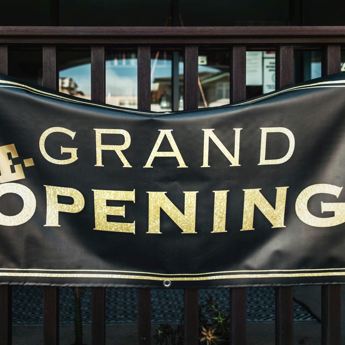Black and gold outdoor banner announcing a re-opening